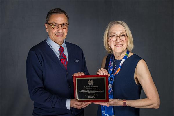 A man and woman are holding a plaque together and smiling at the camera.